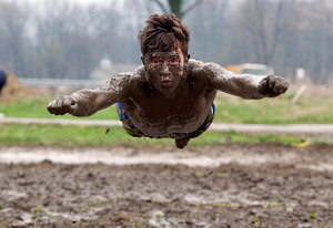A student jumping into mud on Muddy Sunday