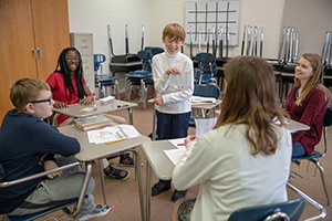 Notre Dame students Natalie Casal (center, back facing camera) and Emma Jones (right) work with students (left-right) Cameron Cook, Braiona Jones and Levi Pieri (standing) during their Latin class at Clay International Academy. Photo by Barbara Johnston/University of Notre Dame.