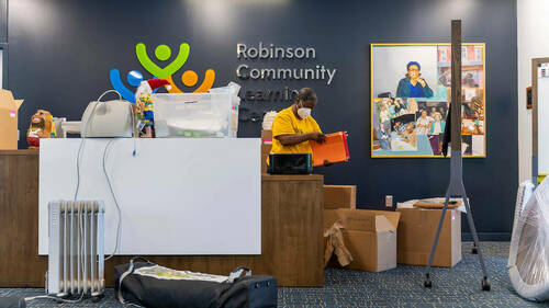 Luella Webster, adult programs coordinator, unpacks boxes behind the reception desk at the new Robinson Community Learning Center (RCLC) in South Bend. Photo by Barbara Johnston/University of Notre Dame.