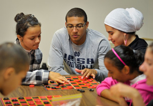 Notre Dame Football player Robert Blanton plays checkers with Michiana refugee children at the Red Cross of St. Joseph County in South Bend