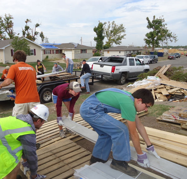 Members of the Notre Dame drumline and trombone section work with other volunteers in a Joplin neighborhood