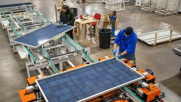 Two men assembling solar panels.