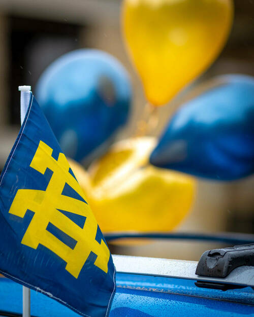 A small Notre Dame flag waves in front of blue and gold balloons