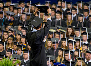 A male student raises his diploma to the crowd