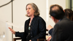 Professor Schirch leads a discussion with a panel of presenters during a symposium.