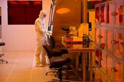 A scientist in a white lab suit uses tools in a Clean Room.