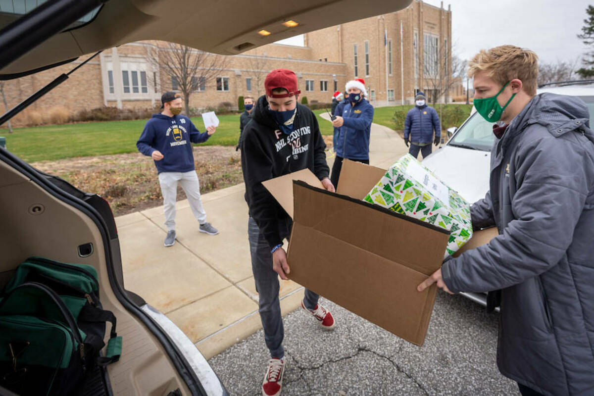Notre Dame Hockey team members Brady Bjork, left, and Spencer Stastney load gifts into a car outside the Compton Family Ice Arena. (Photo by Matt Cashore/University of Notre Dame)