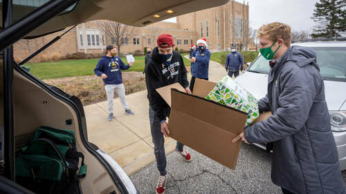 Notre Dame Hockey team members Brady Bjork, left, and Spencer Stastney load gifts into a car outside the Compton Family Ice Arena. (Photo by Matt Cashore/University of Notre Dame)