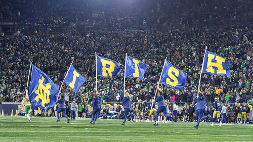 Cheerleaders carry flags after a touchdown. (Photo by Matt Cashore)