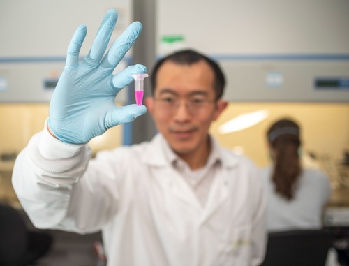 Donny Hanjaya Putra, assistant professor of aerospace and mechanical engineering, holds a vial of specially engineered nanoparticle "backpacks."