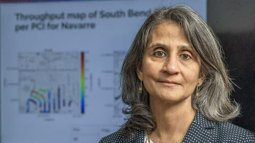 Professor Monisha Ghosh, female, is pictured in front of a presentation related to spectrum wireless technologies.
