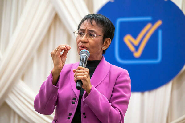 Maria Ressa speaks at Notre Dame using a handheld microphone in front a backdrop of the 2024 Forum logo