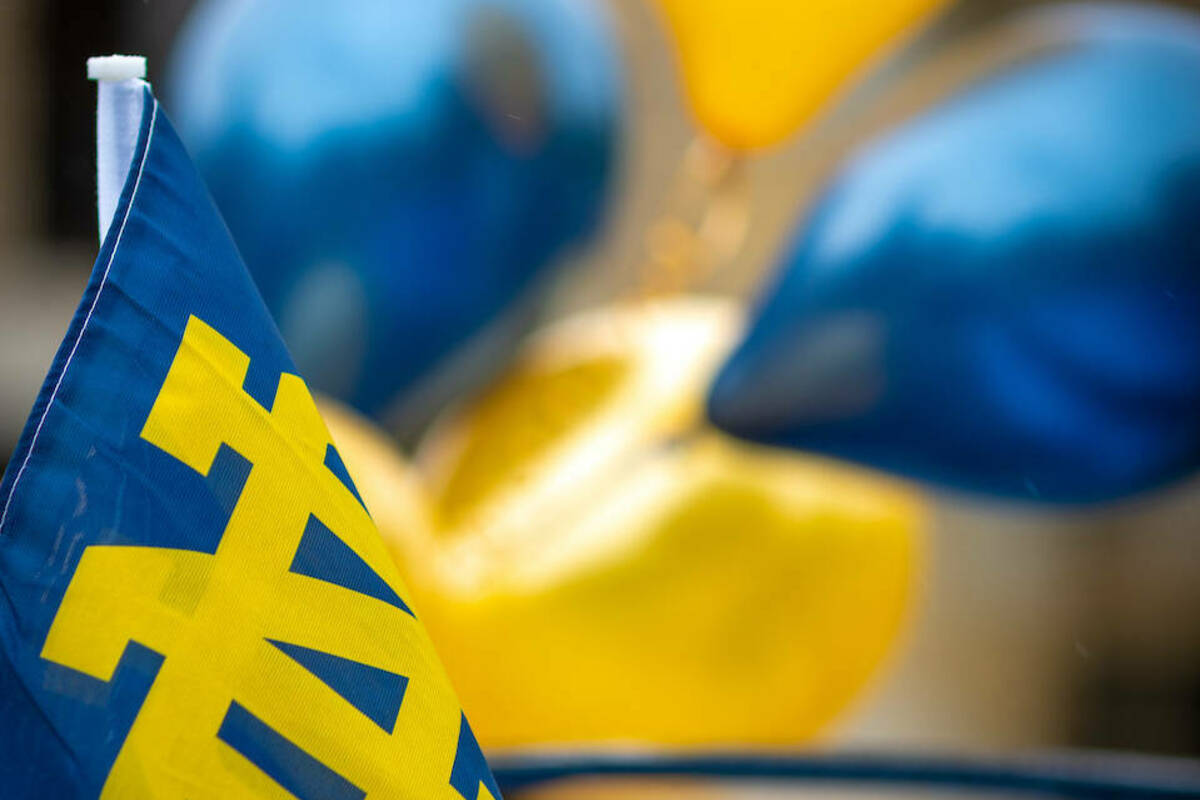 A small Notre Dame flag waves in front of blue and gold balloons