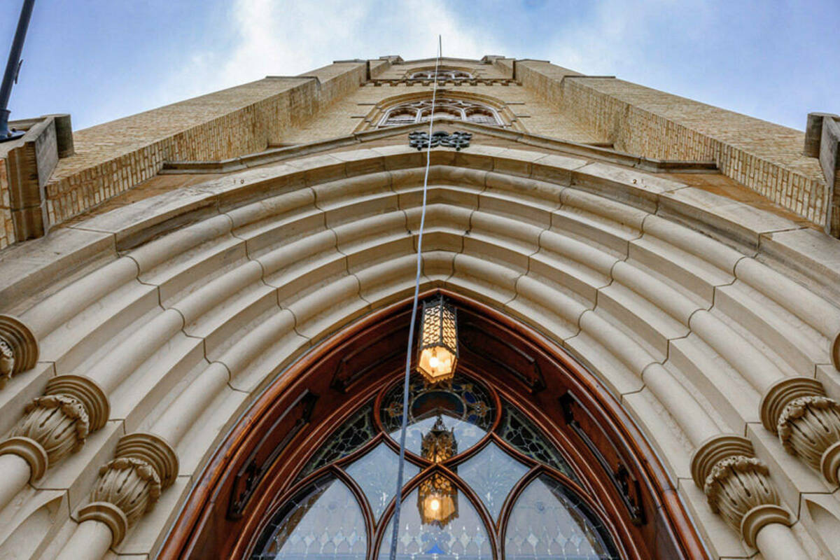From below looking up, a transmission wire is dangling from a high steeple window of the basilica on the University of Notre Dame campus.