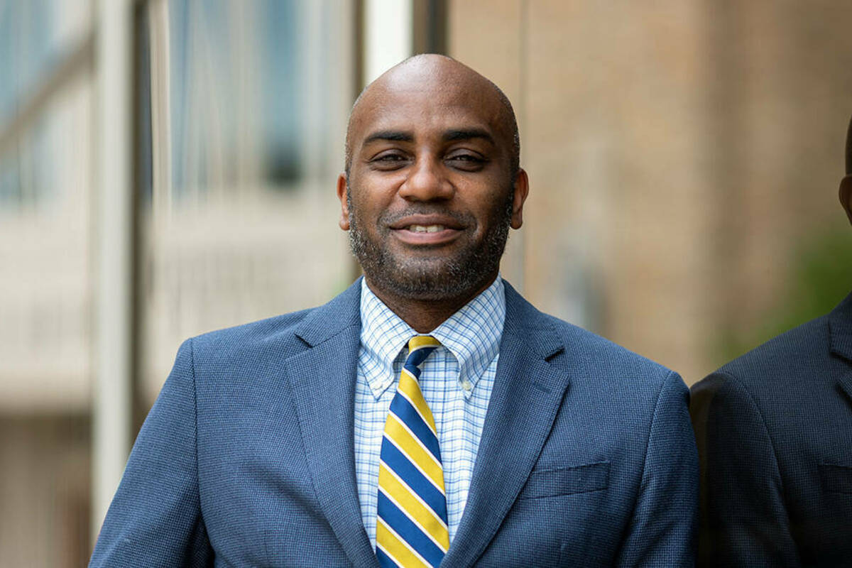 Ernest Morrell, the Coyle Professor of Literacy Education, is pictured in a professional headshot wearing a blue suit and blue and gold tie, outside leaning against a building