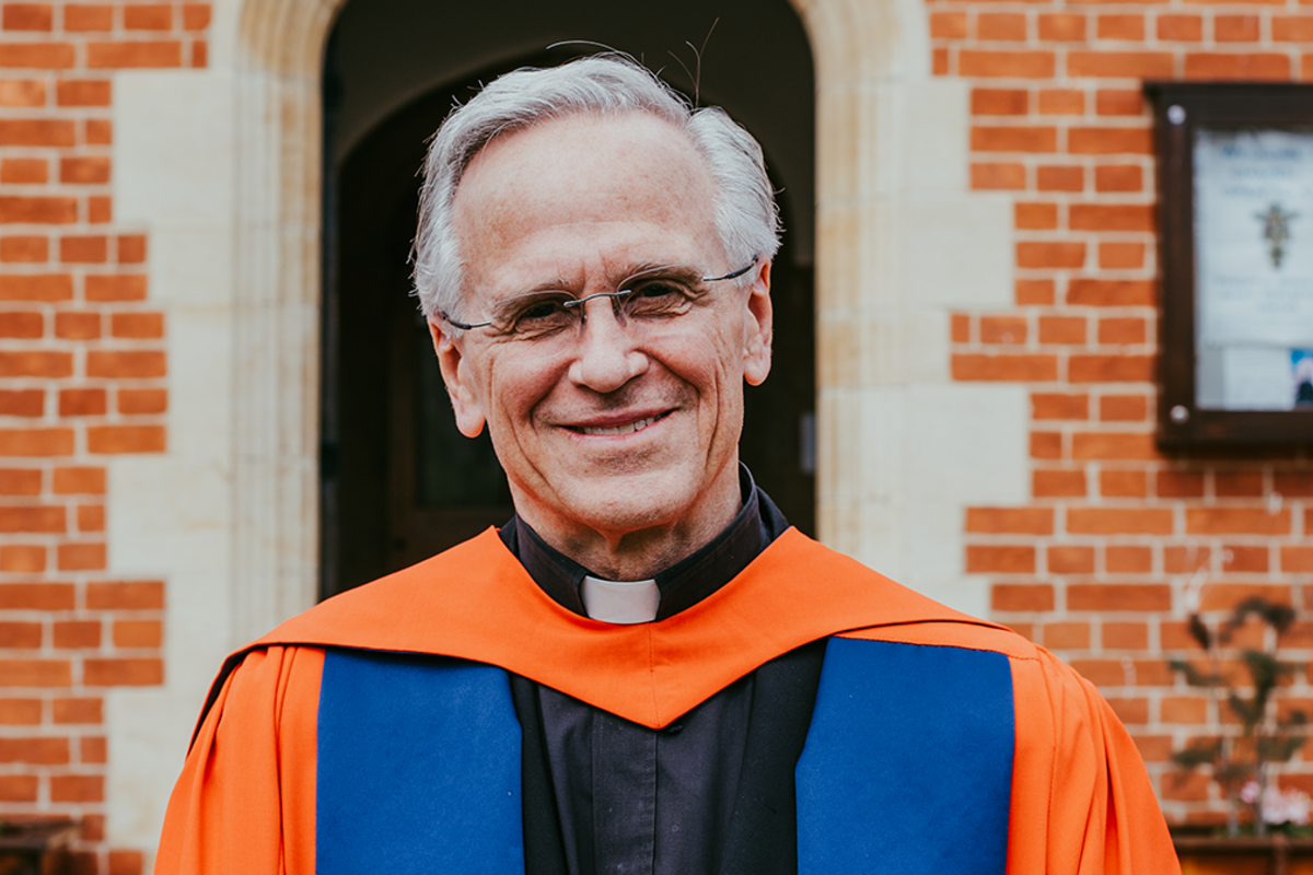 Former Notre Dame President Rev. John I. Jenkins, C.S.C., smiling in a blue and orange robe.