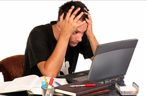 A man sitting in front of a computer with his head in his hands